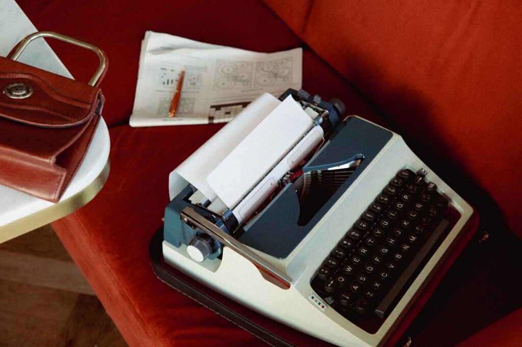 Old typewriter and handbag on a red couch